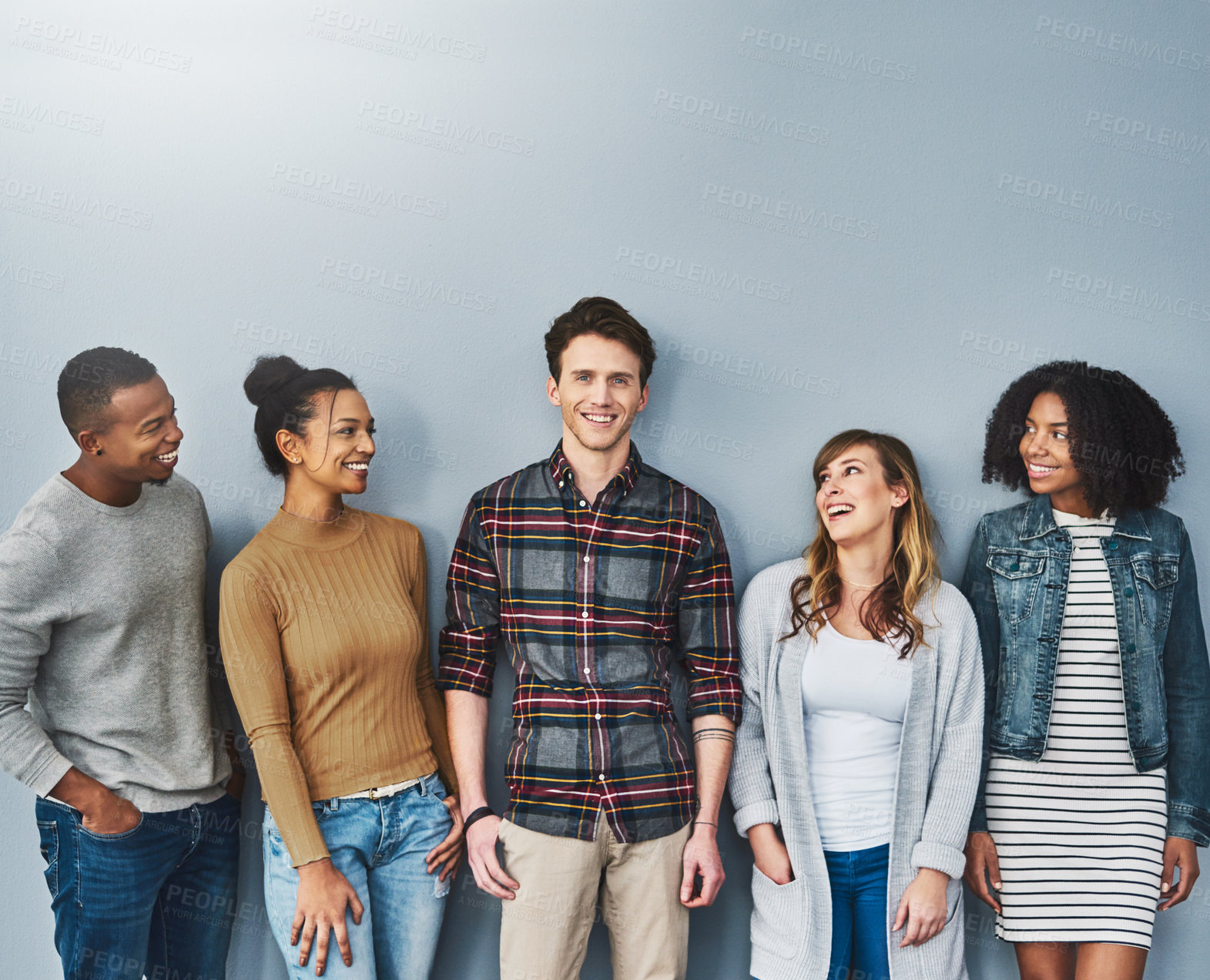 Buy stock photo Studio portrait of a diverse group of young people standing together against a gray background