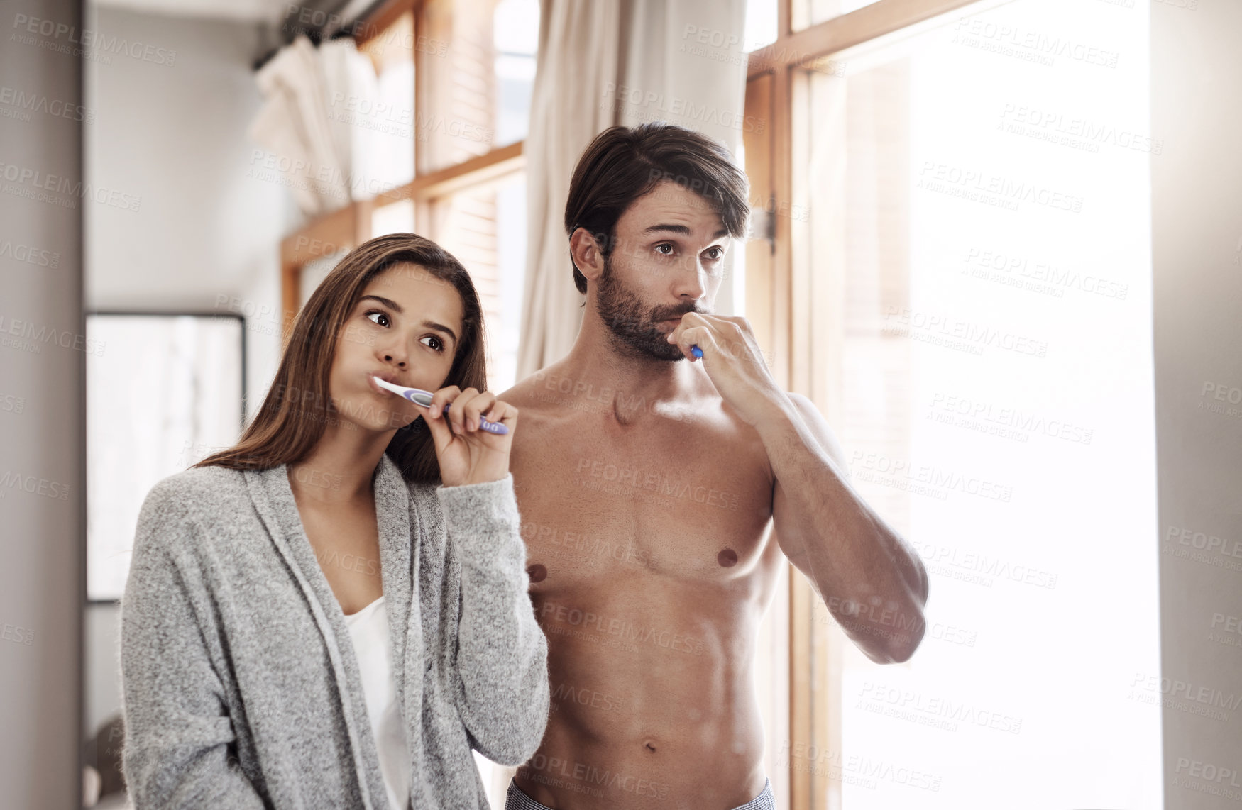Buy stock photo Shot of a young couple brushing their teeth together at home