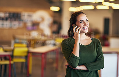 Buy stock photo Shot of a confident young woman talking on her cellphone while standing in an modern office