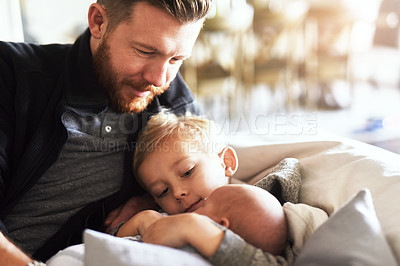 Buy stock photo Shot of young man hanging out on the sofa with his two little boys at home during the day