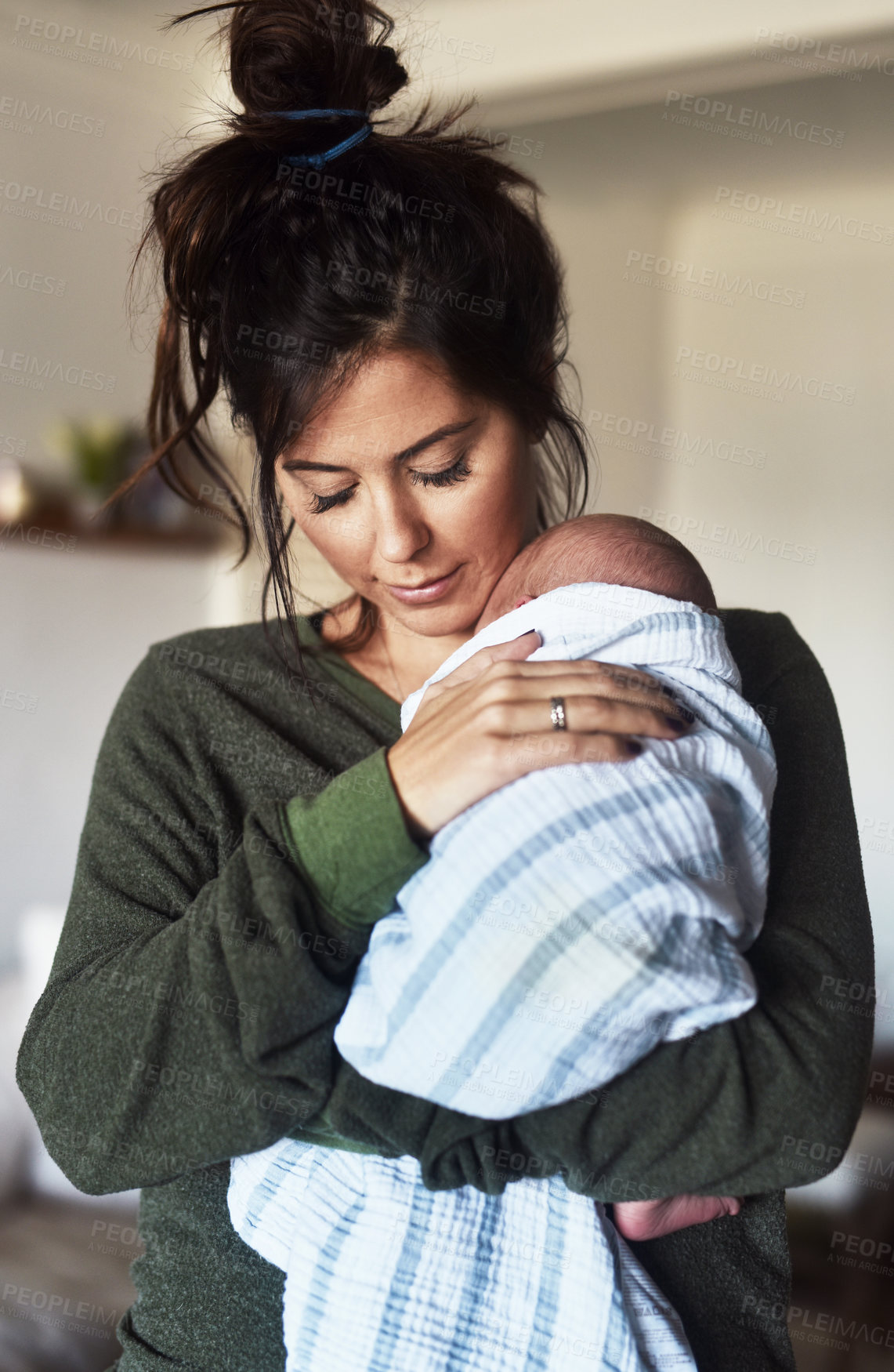 Buy stock photo Shot of a cheerful young woman holding her little infant son at home during the day
