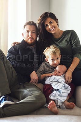 Buy stock photo Portrait of a cheerful young family seated on a sofa together at home during the day