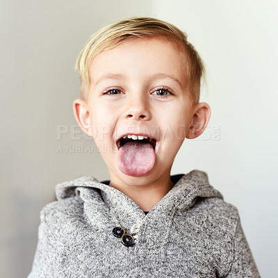 Buy stock photo Portrait of a cheerful little boy sticking his tongue out at home during the day