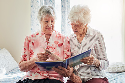 Buy stock photo Shot of two elderly women looking through a photo album together