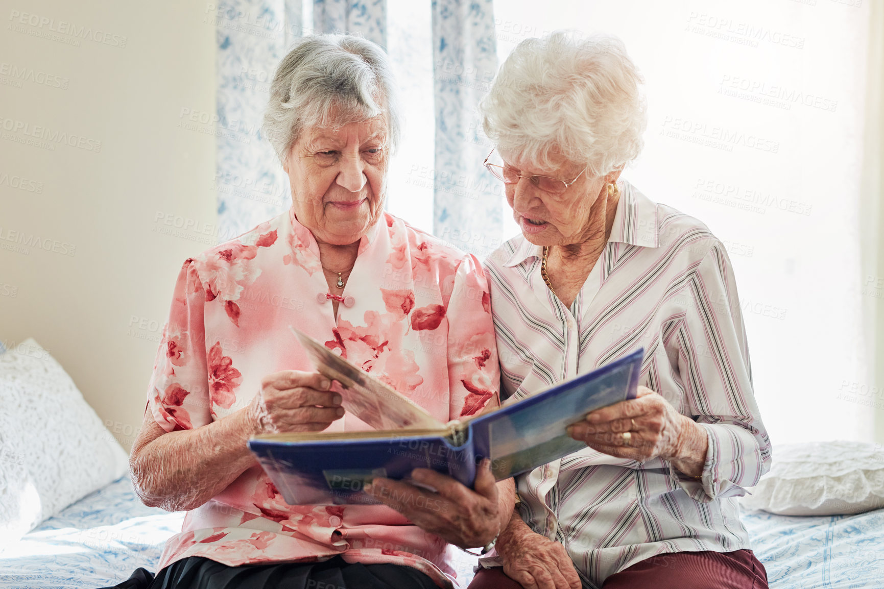 Buy stock photo Shot of two elderly women looking through a photo album together