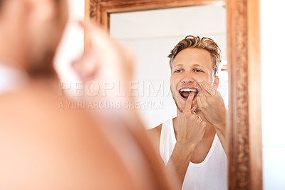 Buy stock photo Shot of a young man flossing his teeth at home