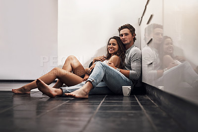 Buy stock photo Shot of an affectionate young couple sitting on the kitchen floor