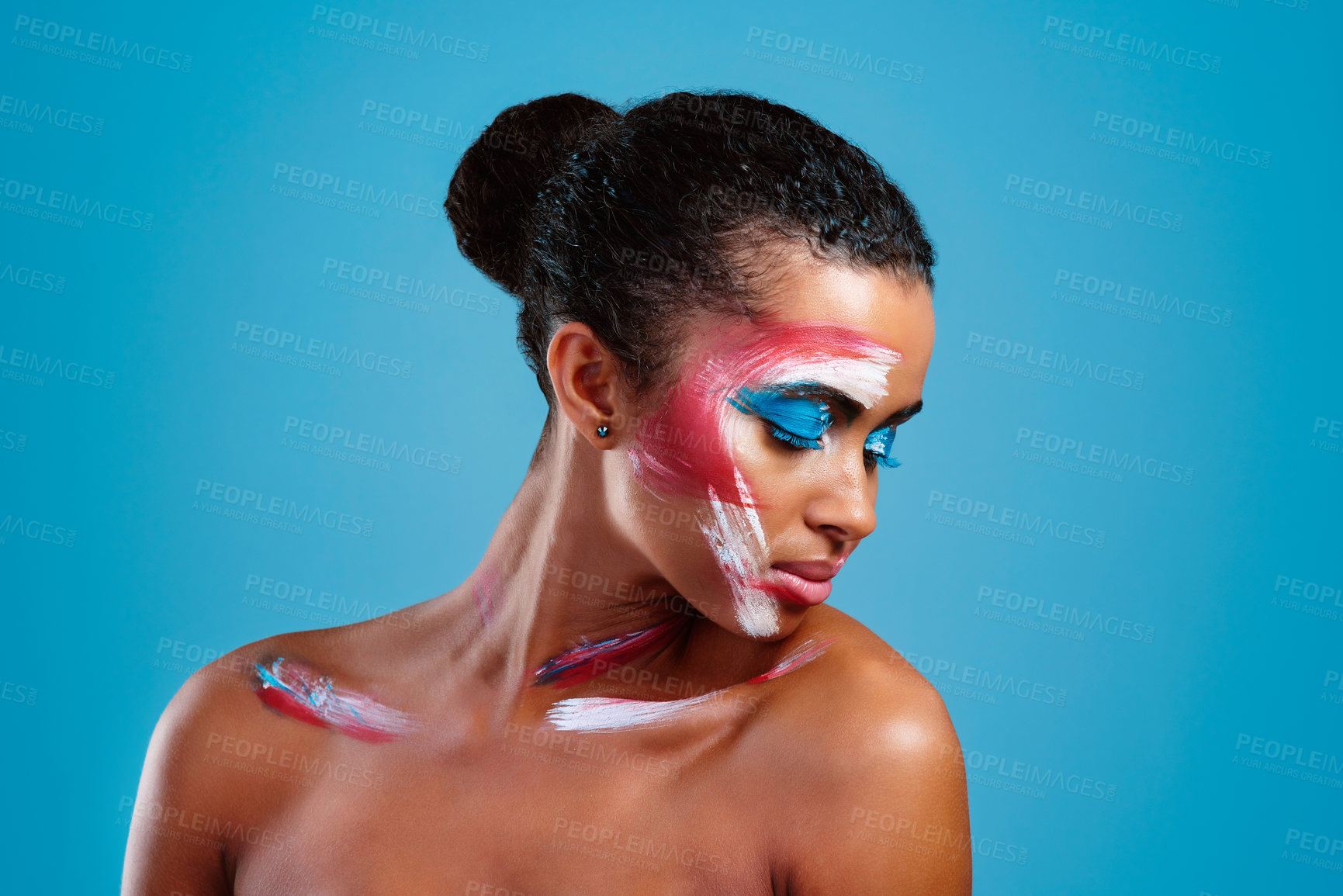 Buy stock photo Studio shot of a beautiful young woman covered in face paint posing against a blue background