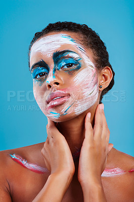Buy stock photo Studio portrait of a beautiful young woman covered in face paint posing against a blue background