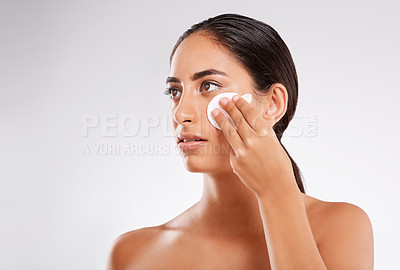 Buy stock photo Studio shot of a beautiful young woman applying lotion while posing against a gray background