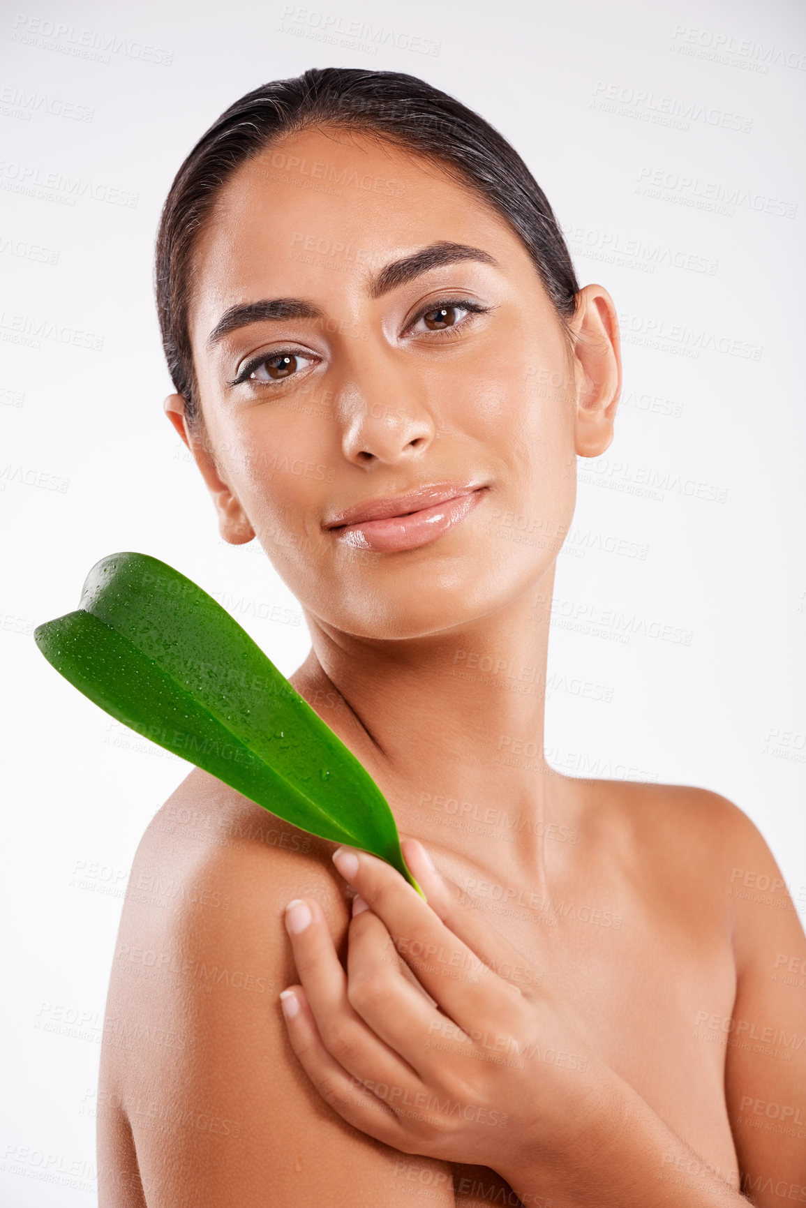 Buy stock photo Studio portrait of a beautiful young woman holding a eucalyptus leaf against a gray background