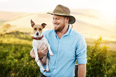 Buy stock photo Shot of a farmer holding his dog in a vineyard