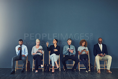 Buy stock photo Studio shot of a group of businesspeople using wireless devices while waiting in line