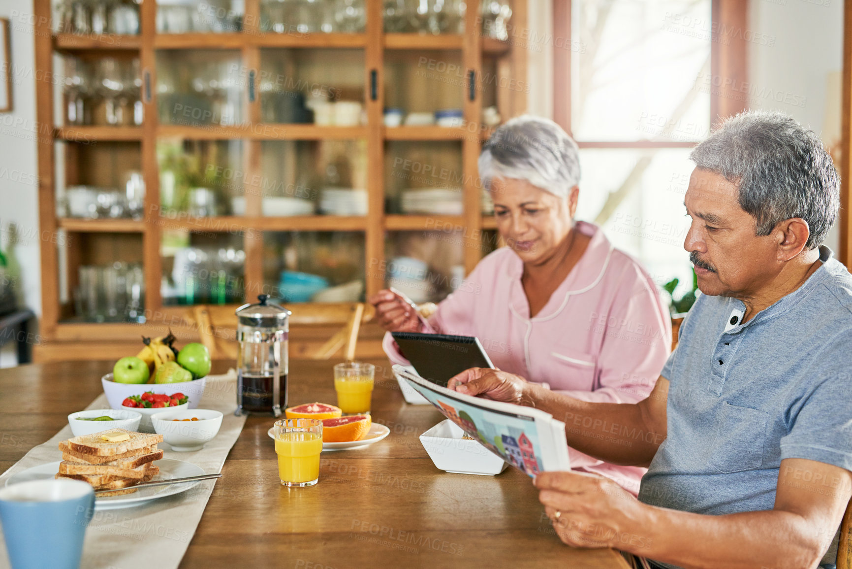 Buy stock photo Newspaper, eating breakfast and senior couple with tablet for reading morning news, story and update. Food, man and woman with technology in retirement home for article, online information and relax