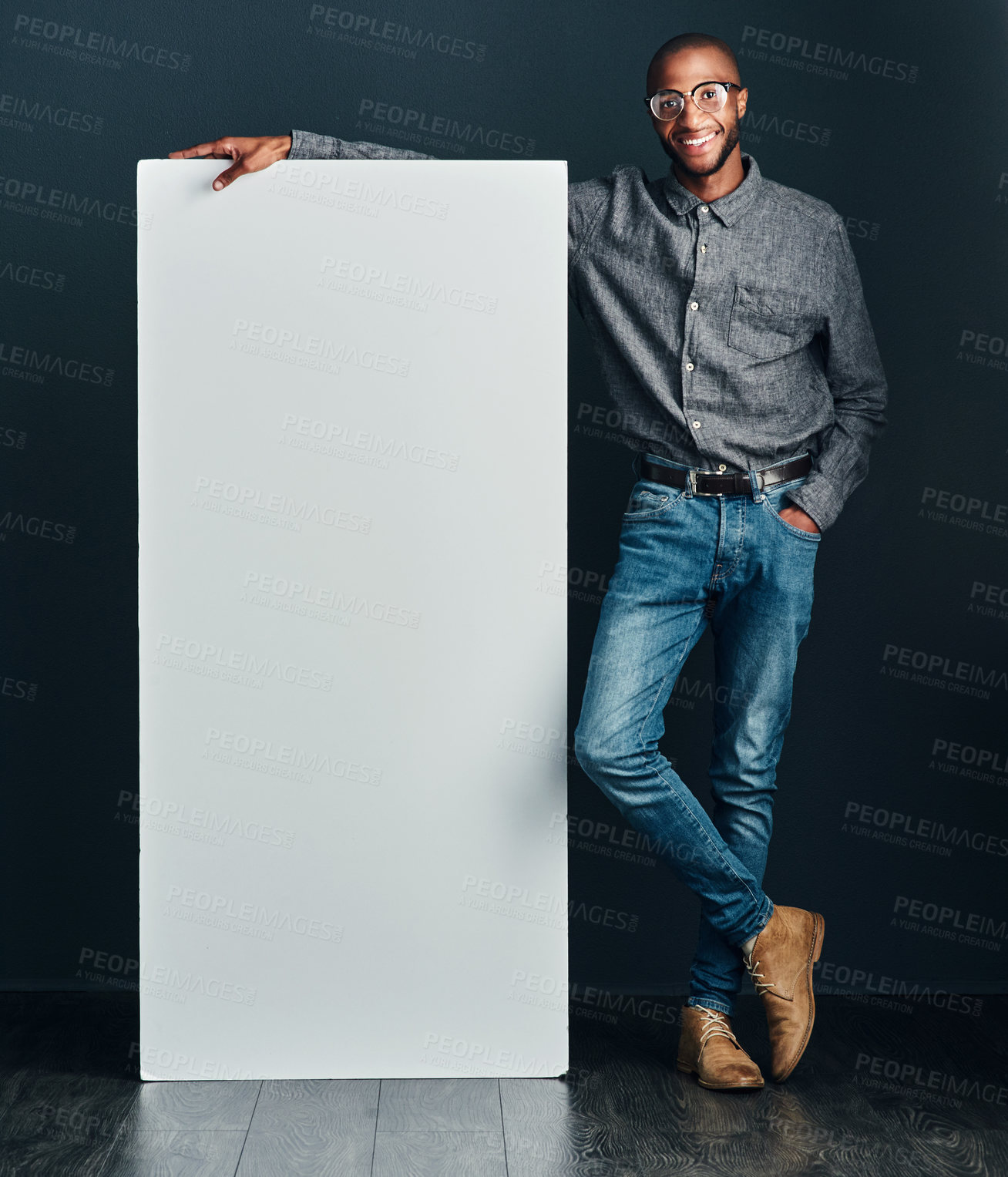Buy stock photo Shot of a handsome young man standing next to a blank placard