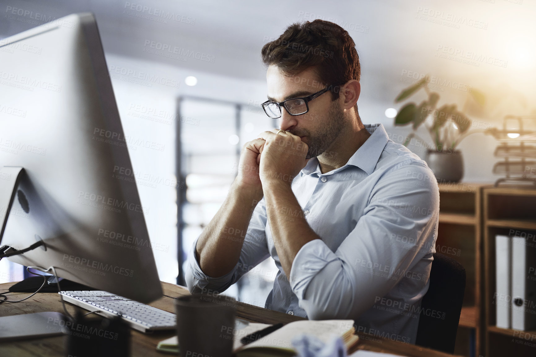 Buy stock photo Shot of a young businessman working late on a computer in an office