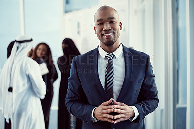 Buy stock photo Cropped portrait of a handsome young businessman standing in the office with his colleagues in the background