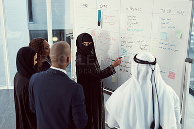 Buy stock photo High angle shot of a group of diverse business colleagues working together on a whiteboard in their office