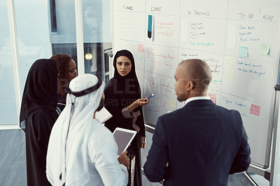 Buy stock photo High angle shot of a group of diverse business colleagues working together on a whiteboard in their office