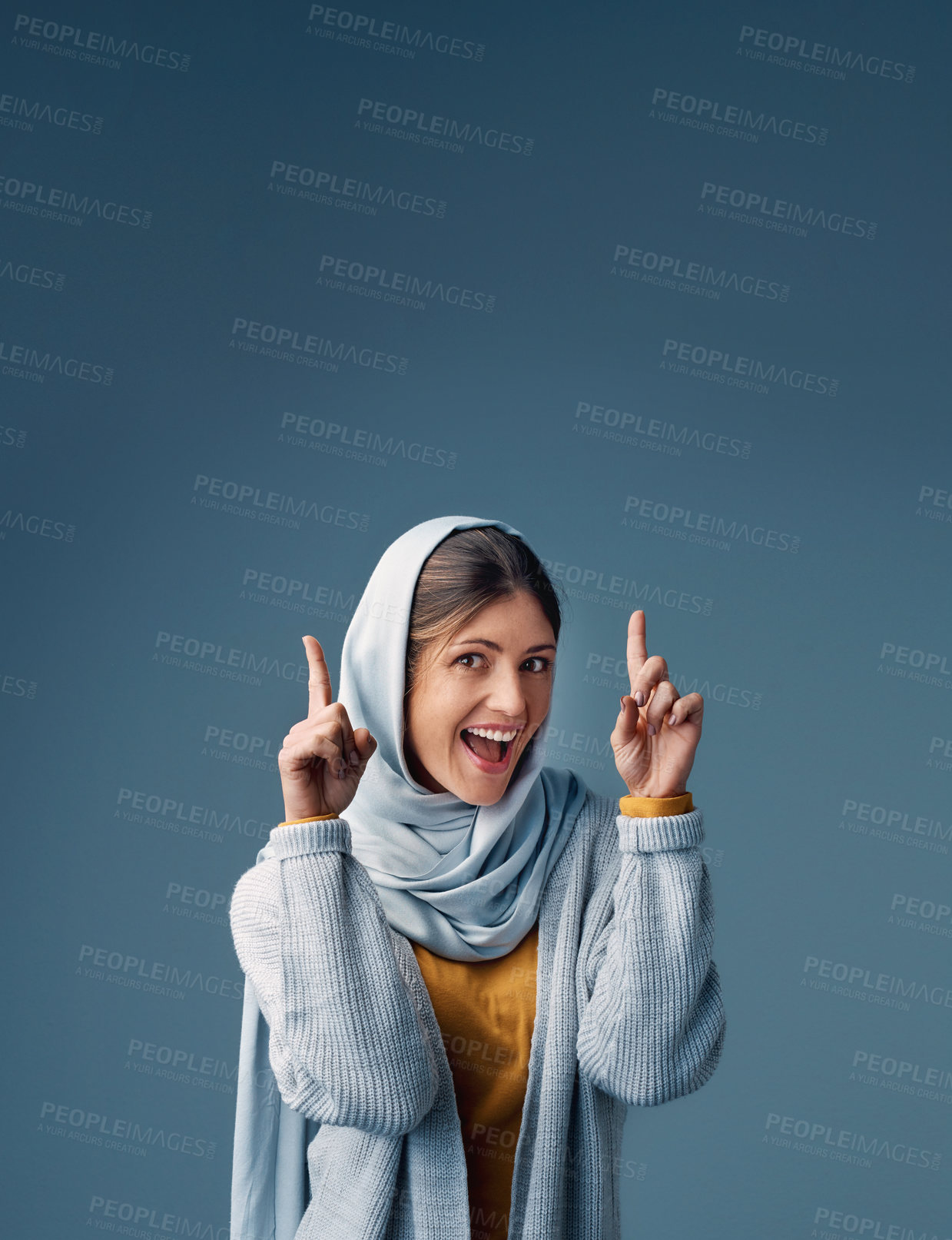 Buy stock photo Pointing, woman and hijab in studio, portrait and isolated on blue background. Finger, point and mockup for deal or retail sale advert with female model, muslim and smile with hand for announcement