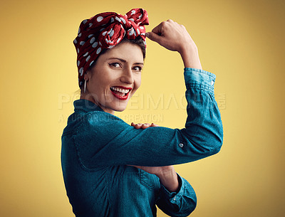 Buy stock photo Studio portrait of an attractive young woman flexing her bicep while standing against a yellow background