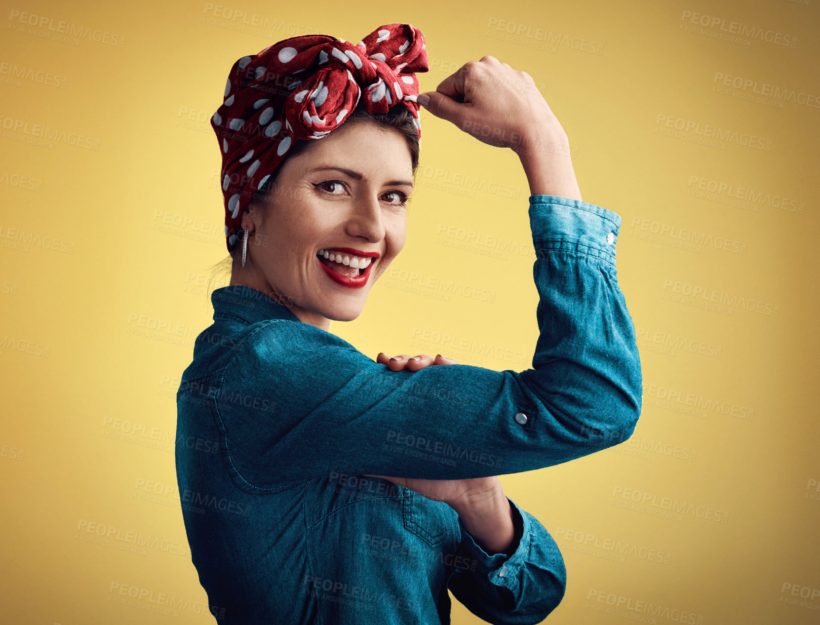 Buy stock photo Studio portrait of an attractive young woman flexing her bicep while standing against a yellow background
