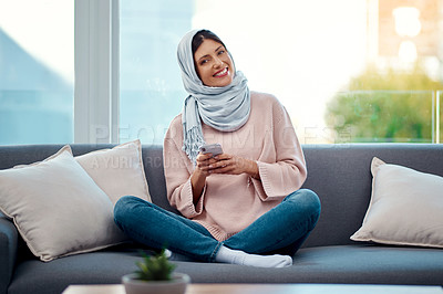 Buy stock photo Smile, phone and portrait of muslim woman on sofa typing email on mobile app or internet at home. happy, technology and islamic female person scroll on cellphone and relaxing in living room at house.