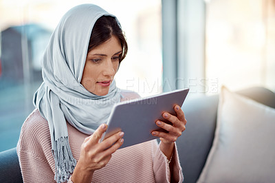 Buy stock photo Relax, reading and muslim woman with tablet on sofa for online ebook in living room at home. Rest digital technology and islamic female person enjoying internet story, novel or literature in house.