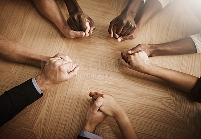 Buy stock photo Group of diverse business people holding their hands together in solidarity on a table. Colleagues in unity supporting one another, prayer in the office space between co workers. 
