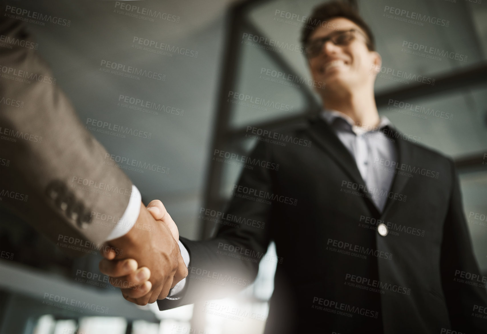 Buy stock photo Below of two business people's handshake during a meeting in an office. Colleagues finalize a successful promotion, deal and merger. Coworkers greet while collaborating and negotiating in interview