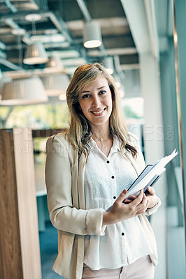 Buy stock photo Portrait of a confident young businesswoman holding a digital tablet while standing inside of the office during the day