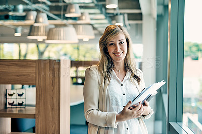 Buy stock photo Portrait of a confident young businesswoman holding a digital tablet while standing inside of the office during the day