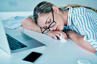 Buy stock photo Shot of a tired looking young businesswoman sleeping on her desk in the office at work during the day