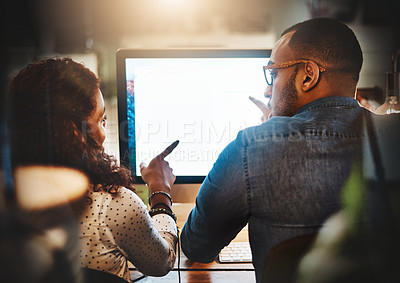Buy stock photo Rearview shot of a young businessman and businesswoman using a computer together during a late night at work