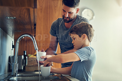Buy stock photo Shot of a father and son washing dishes together at home