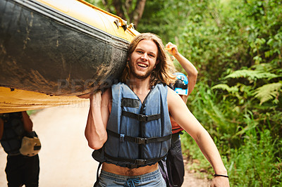 Buy stock photo Cropped portrait of a handsome young man and his friends carrying their raft towards the water