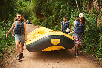 Buy stock photo Full length portrait of a handsome young man and his friends carrying their raft towards the water