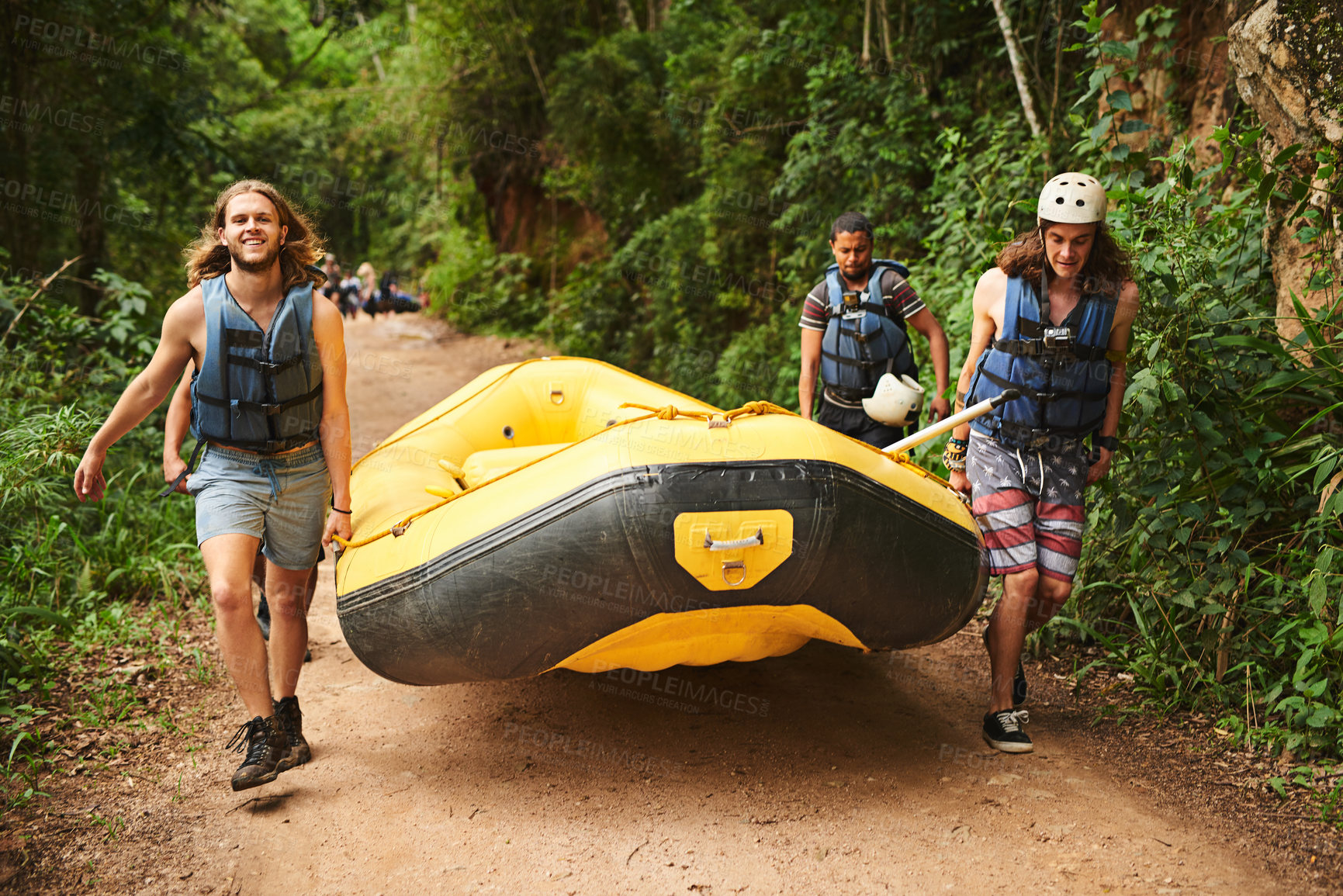 Buy stock photo Full length portrait of a handsome young man and his friends carrying their raft towards the water