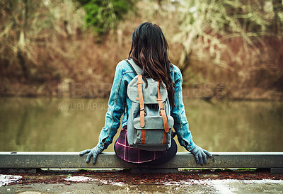 Buy stock photo Rearview shot of an unrecognizable woman sitting by a lake outdoors