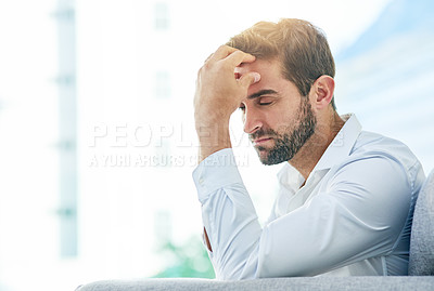 Buy stock photo Shot of a young carefree man seated on a sofa while contemplating during the day