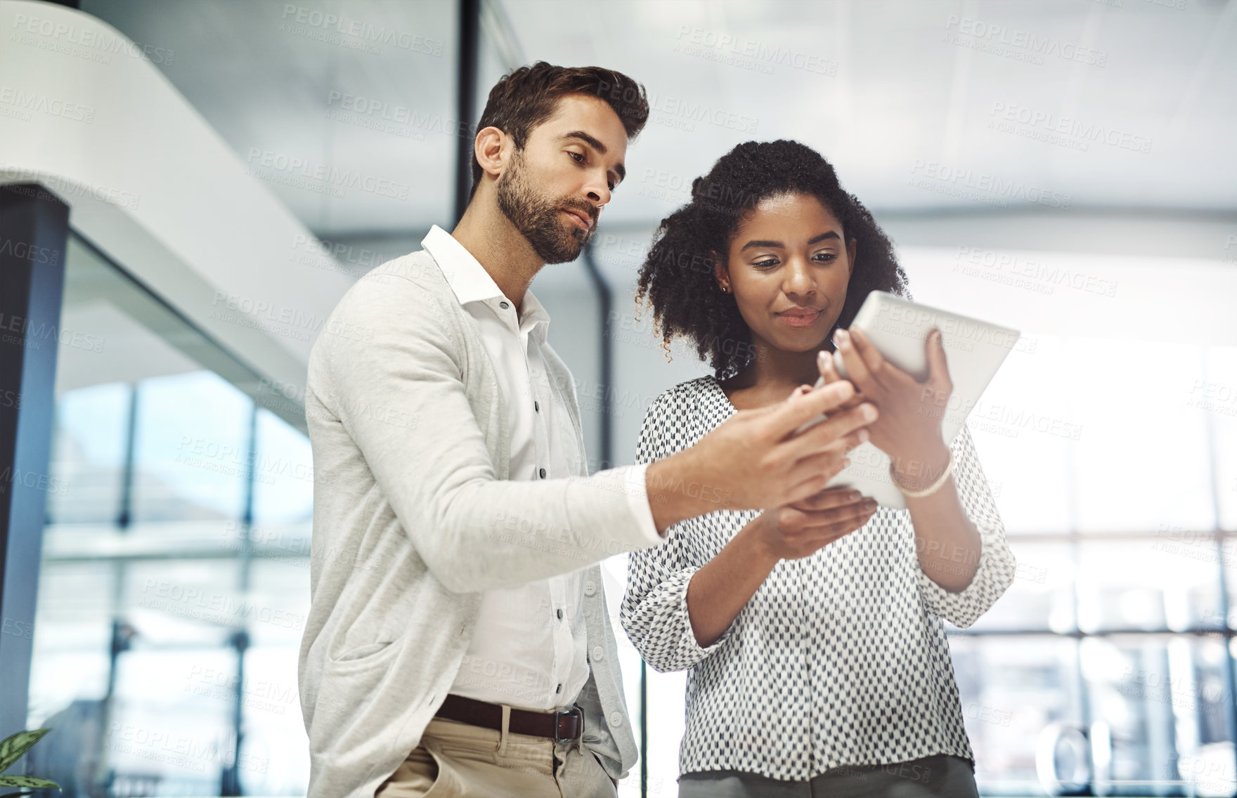 Buy stock photo Shot of two businesspeople discussing something on a digital tablet