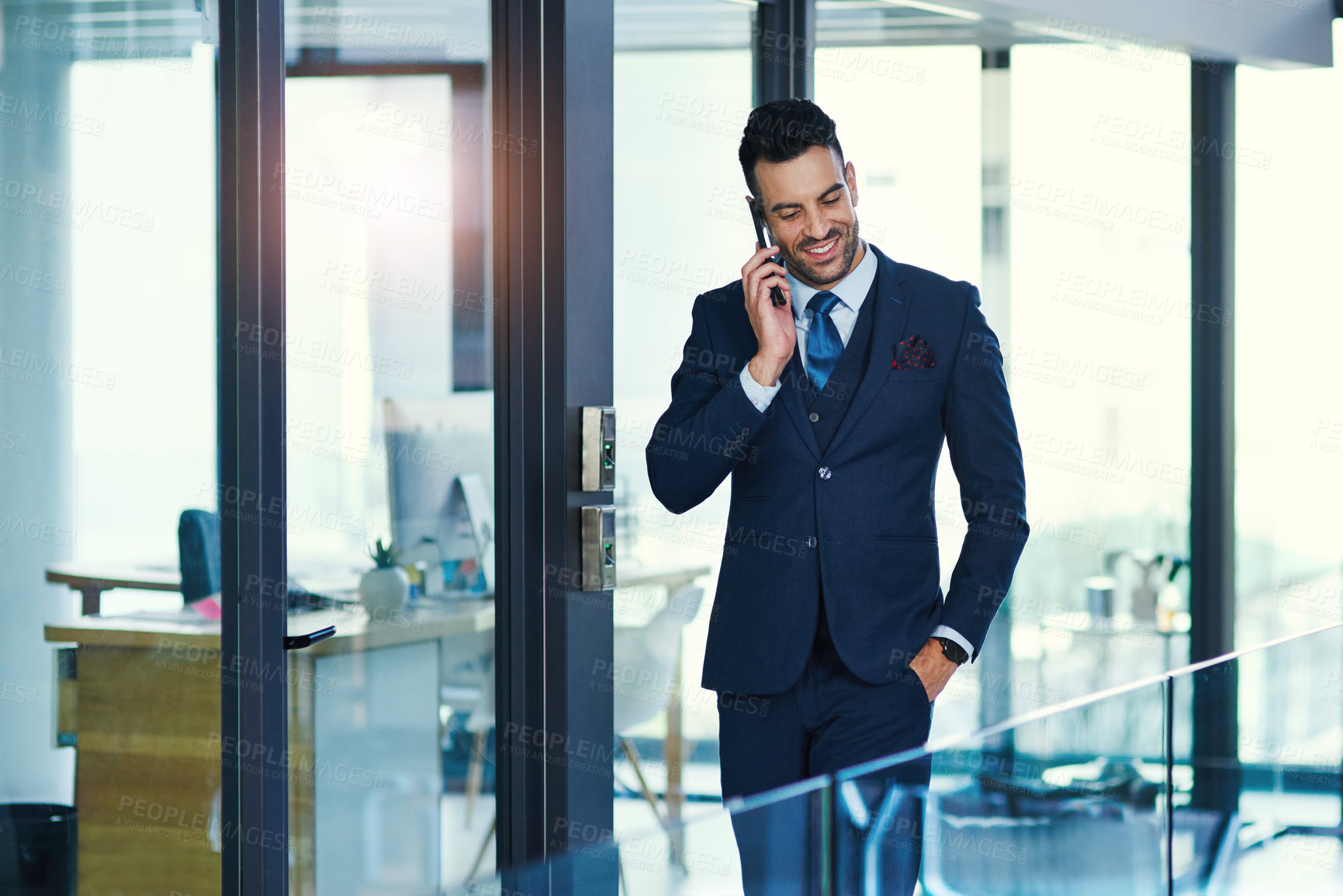 Buy stock photo Shot of a young businessman talking on a cellphone in an office