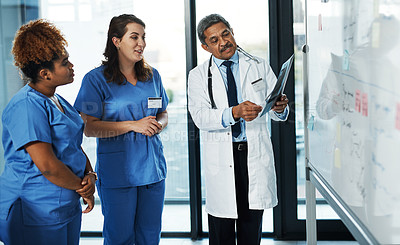 Buy stock photo Shot of a team of doctors discussing the results of an X-ray in a hospital