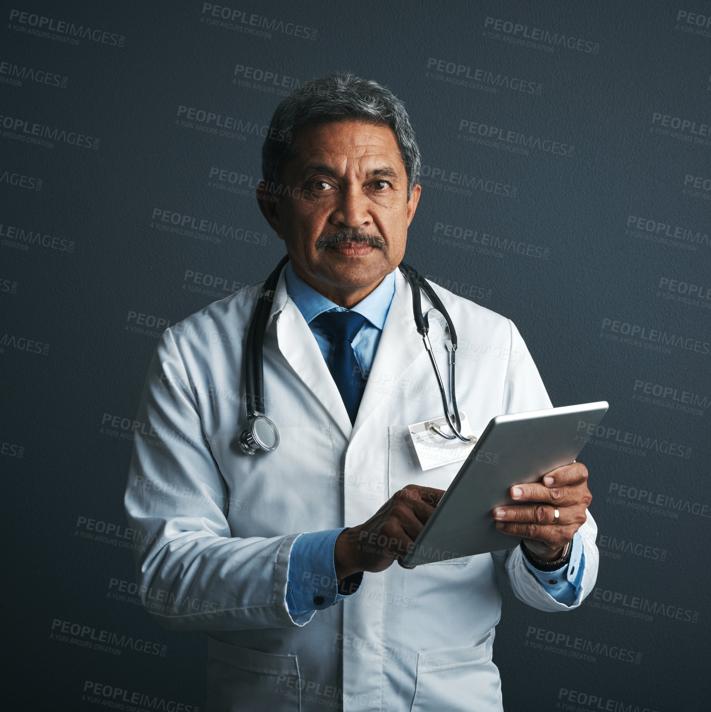 Buy stock photo Studio shot of a mature doctor using a digital tablet against a gray background