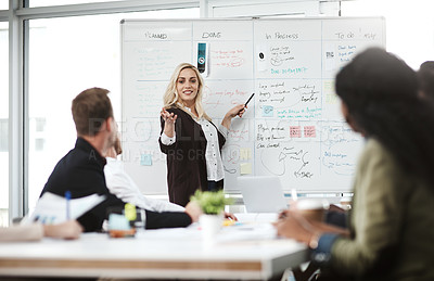 Buy stock photo Shot of a businesswoman giving a presentation to her colleagues on a whiteboard in a boardroom