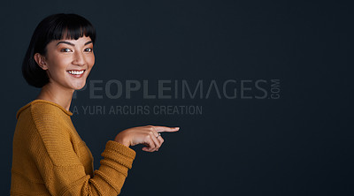 Buy stock photo Woman is pointing, marketing and mockup space with portrait, smile and promo isolated on dark background. Young female person, happy ambassador and branding with advertising and show in studio