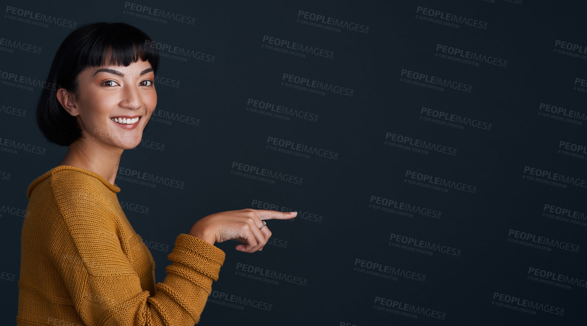 Buy stock photo Woman is pointing, marketing and mockup space with portrait, smile and promo isolated on dark background. Young female person, happy ambassador and branding with advertising and show in studio