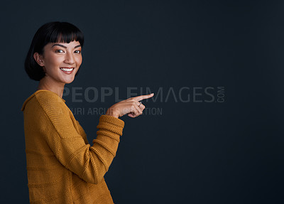 Buy stock photo Woman is pointing, advertising and mockup space with portrait, smile and promo isolated on dark background. Happy female person, ambassador and branding with marketing and presentation in studio