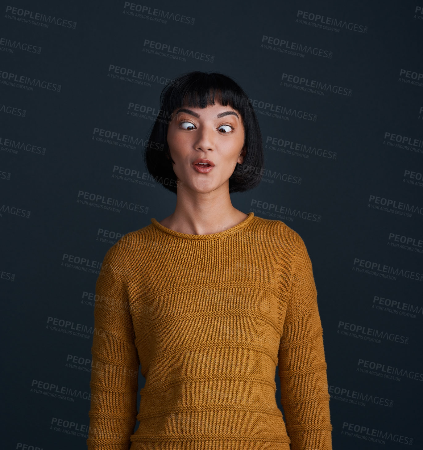 Buy stock photo Studio shot of an attractive young woman crossing her eyes against a dark background
