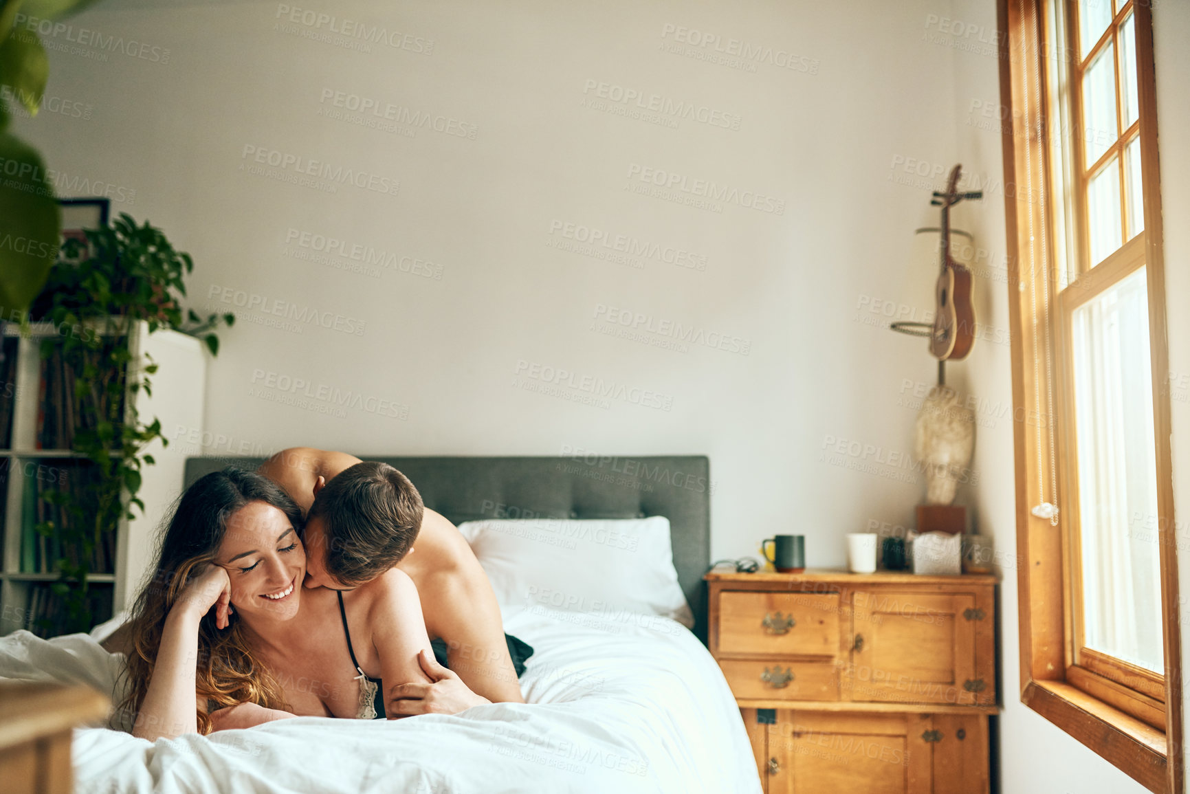 Buy stock photo Shot of an affectionate young couple spending a romantic morning in bed at home